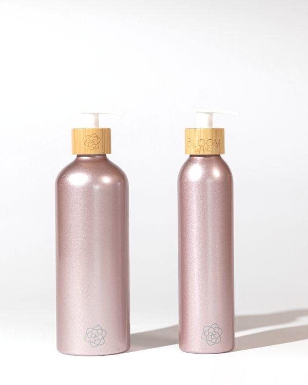 Refillable bathroom dispensers metallic pink with bamboo pump for minimalist bathroom and clean beauty.