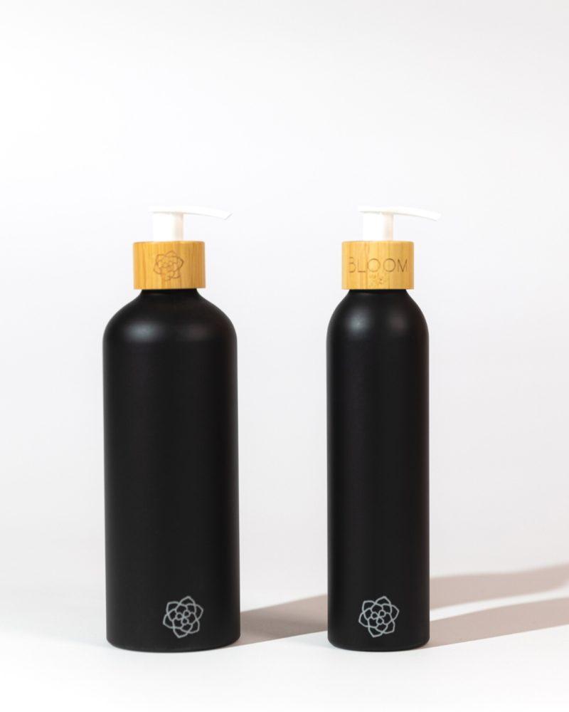 Refillable bathroom dispensers black matte with bamboo pump for eco-chic bathroom.