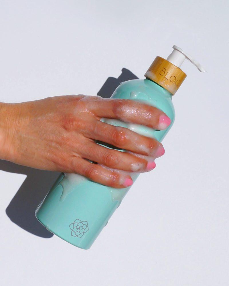 Shampoo bottle dispenser with bamboo pump in pastel green.