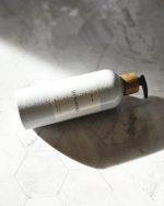 Refillable shampoo bottle in white with bamboo pump for minimalist bathroom.