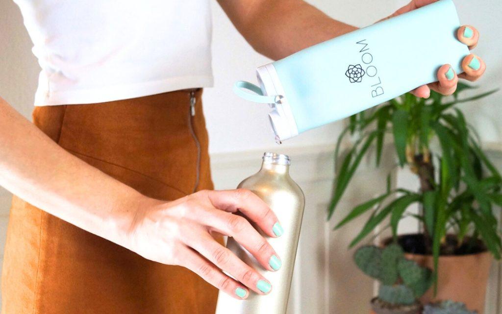 Woman refilling bathroom bottle with eco-friendly shampoo in a minimalist apartment