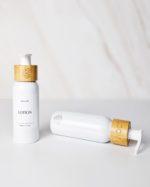Refillable travel bottles in white with bamboo pump for ecofriendly travel toiletries.